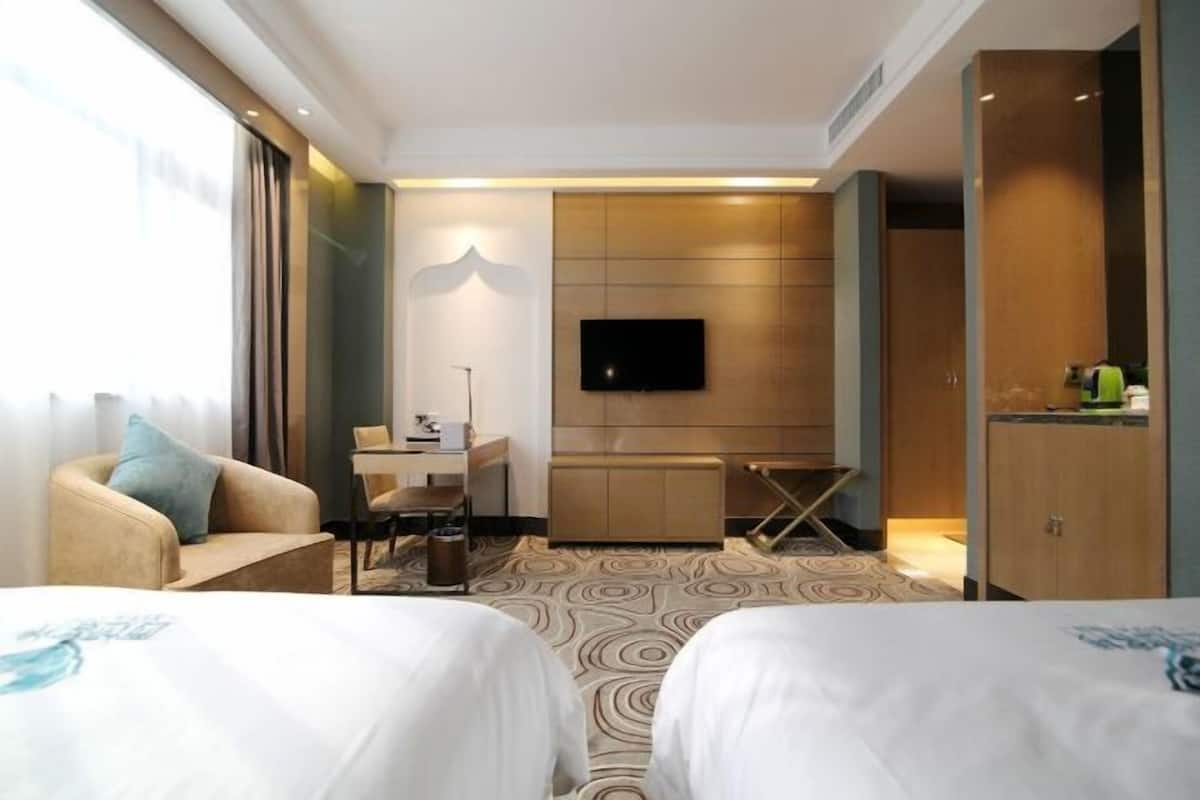 A hotel room with two beds, a desk, a television, and a wardrobe.