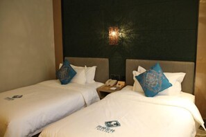 A hotel room with two beds, each with a pillow and a logo on the bedspread. - Xiya Inn (Lanzhou)