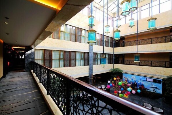 Un atrium à plusieurs niveaux, doté d’une piscine centrale, de lanternes décoratives et d’un escalier.