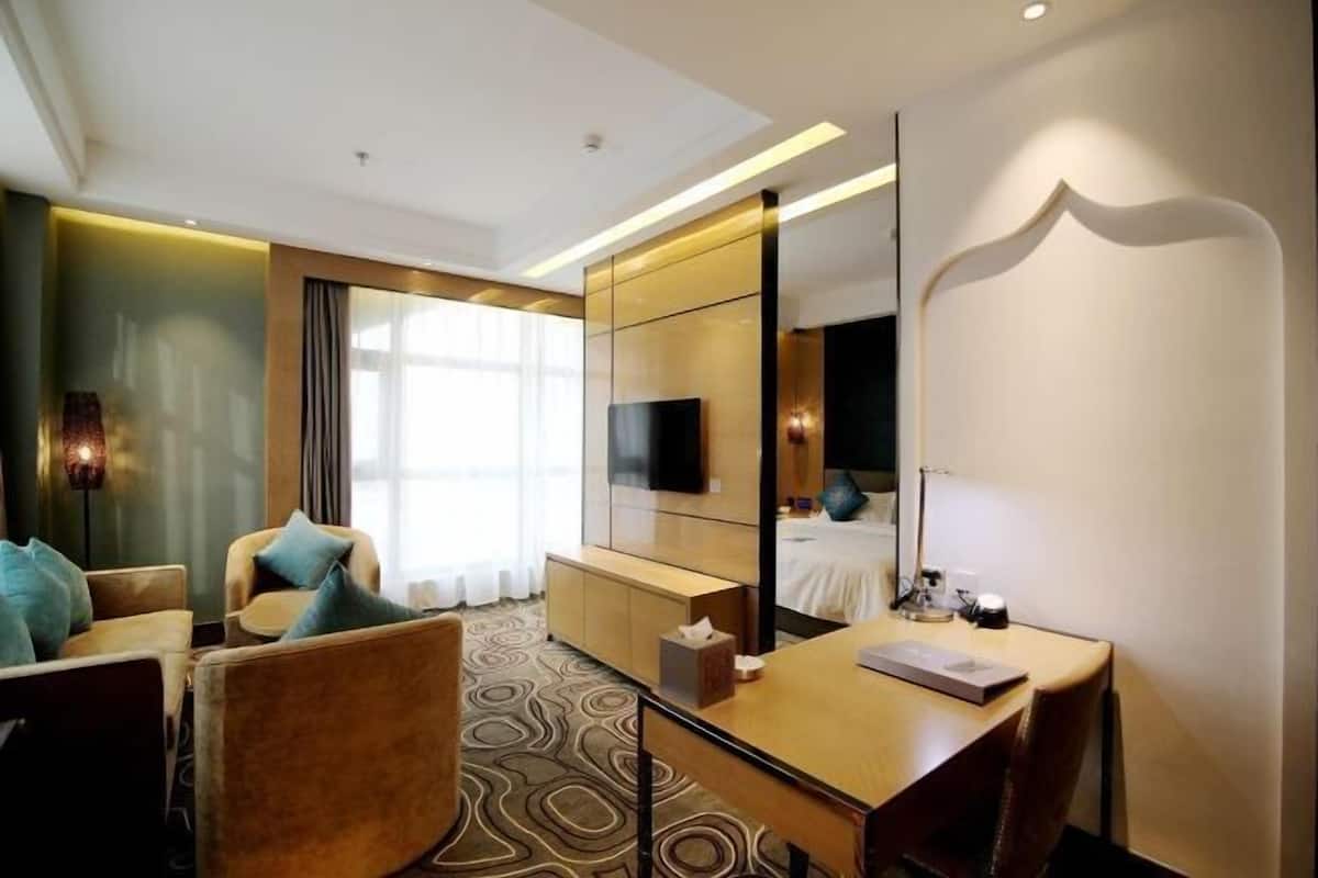 A modern hotel room with a large bed, a desk, a chair, and a television.