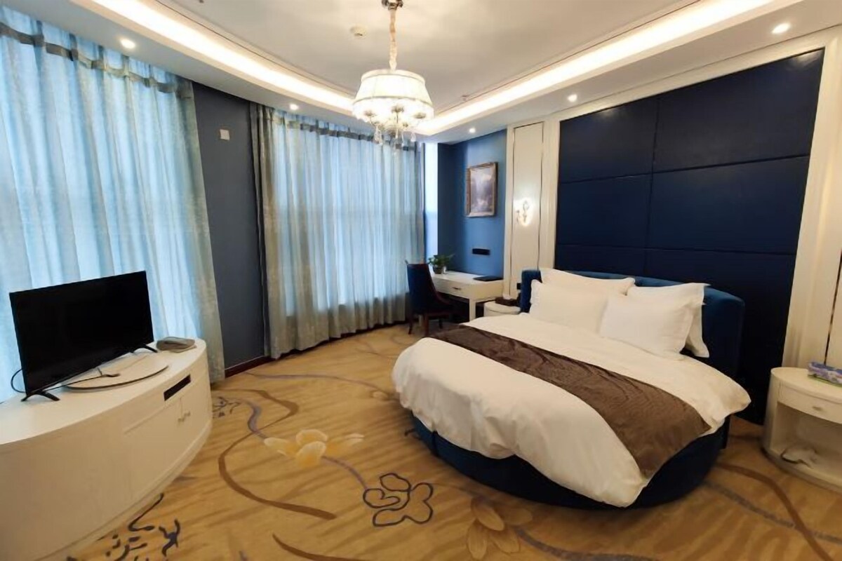 Ein Hotelzimmer mit einem großen Bett, einem Schreibtisch, einem Fernseher und einer Kandelaber.