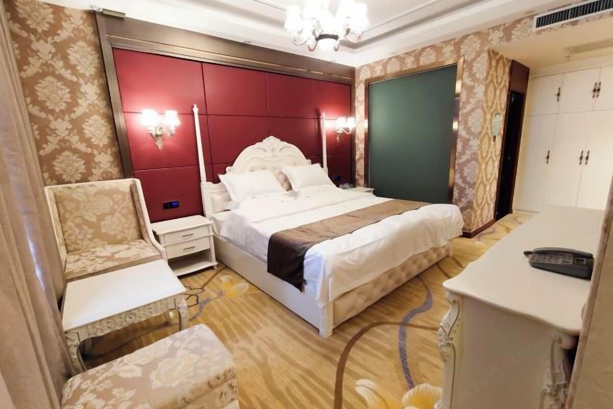 Ein Hotelzimmer mit einem großen Bett, einem Nachttisch, einem Sessel, einem Schreibtisch und einem Kleiderschrank.