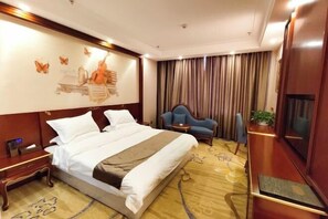A hotel room with a large bed, a desk, a chair, a TV, and a wall with a butterfly mural. - Yixin Hotel (Emin)