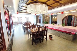 A restaurant with multiple tables and chairs, a chandelier, and a red tablecloth. - Yixin Hotel (Emin)