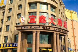 A hotel with a prominent sign indicating it is the Vixin Grand Hotel. - Yixin Hotel (Emin)