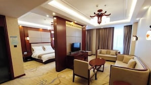 Ein Hotelzimmer mit einem Bett, einem Fernseher, einer Couch, einem Couchtisch und einem Schreibtisch.