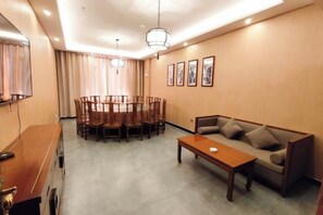 A hotel room with a dining table, chairs, a sofa, a coffee table, and a TV. - Yixin Hotel (Emin)