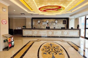 A hotel reception area with a marble counter, a clock, and a decorative ceiling light fixture. - Yixin Hotel (Emin)
