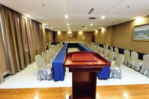 A conference room with a long table, rows of chairs, and a podium. - Yixin Hotel (Emin)