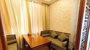 A room with a wooden table, a sofa, and a patterned wall. - Yixin Hotel (Emin)
