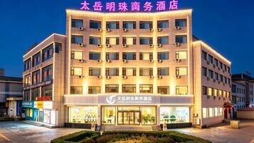 A hotel with multiple floors, a well-lit entrance, and a sign indicating it is a business hotel.