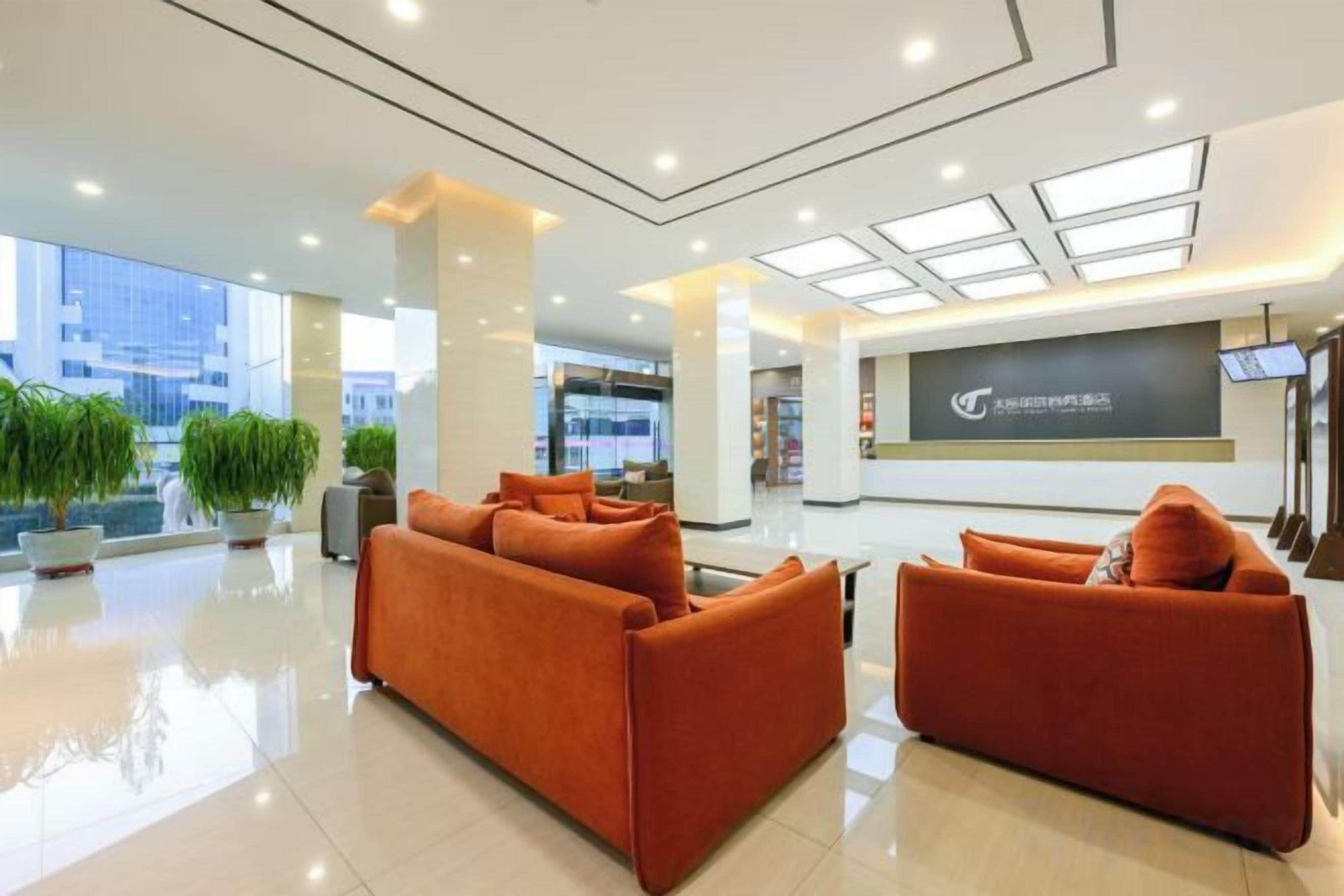 A modern lobby with a reception desk, two sofas, and large windows.