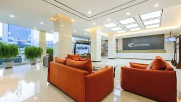 A modern lobby with a reception desk, two sofas, and large windows.