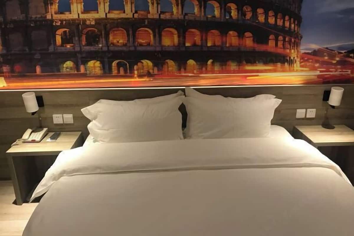 Ein Hotelzimmer mit einem Bett, zwei Nachttischen und einem Wandbild des Kolosseums.