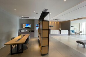 Un vestíbulo moderno de hotel con un mostrador de recepción, zona de estar y una pantalla de televisión.