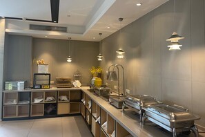 Una cocina moderna con electrodomésticos de acero inoxidable, un sistema de buffet e iluminación colgante.