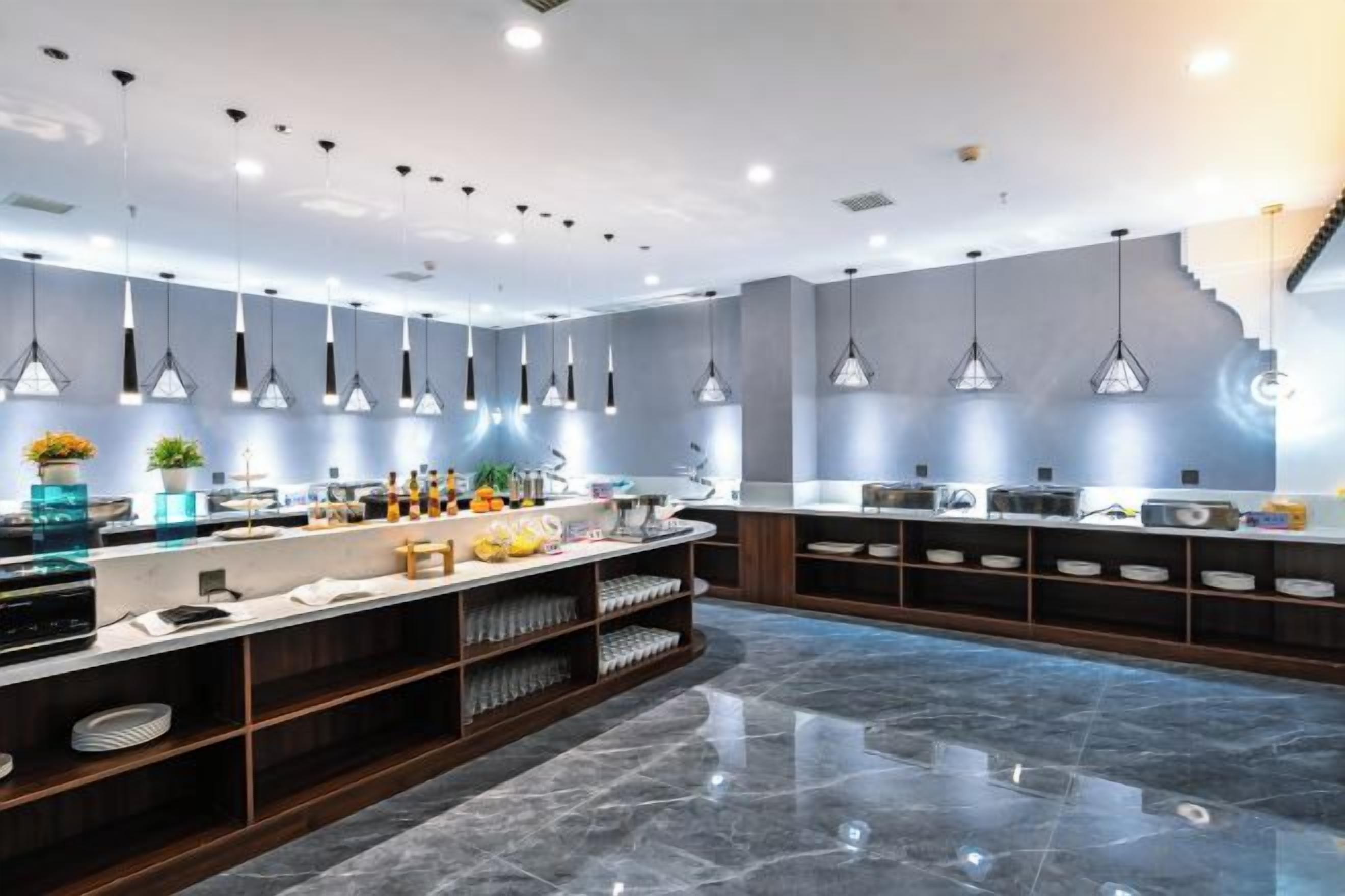 A modern kitchen with pendant lighting, marble countertops, and a central island.