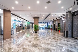 A spacious lobby with a marble floor, a reception desk, and potted plants.