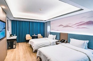 A hotel room with two beds, a desk, a chair, a TV, and a wall with a painting.