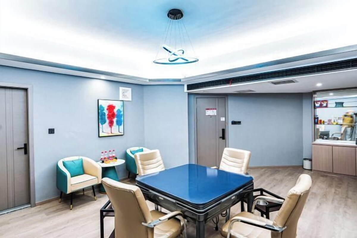 A conference room with a blue table, beige chairs, and a modern ceiling light fixture.