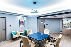 A conference room with a blue table, beige chairs, and a modern ceiling light fixture. - Xiangjun Hotel, Shuangfeng County (Shuangfeng)
