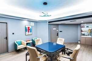 A conference room with a blue table, beige chairs, and a modern ceiling light fixture.