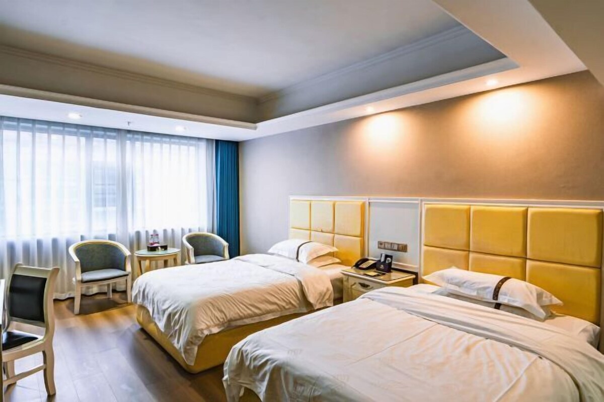 A hotel room with two beds, a desk, and a chair.