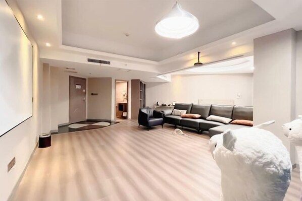 A modern living room with a sectional sofa, a coffee table, and a large light fixture. - Xiangjun Hotel, Shuangfeng County (Shuangfeng)