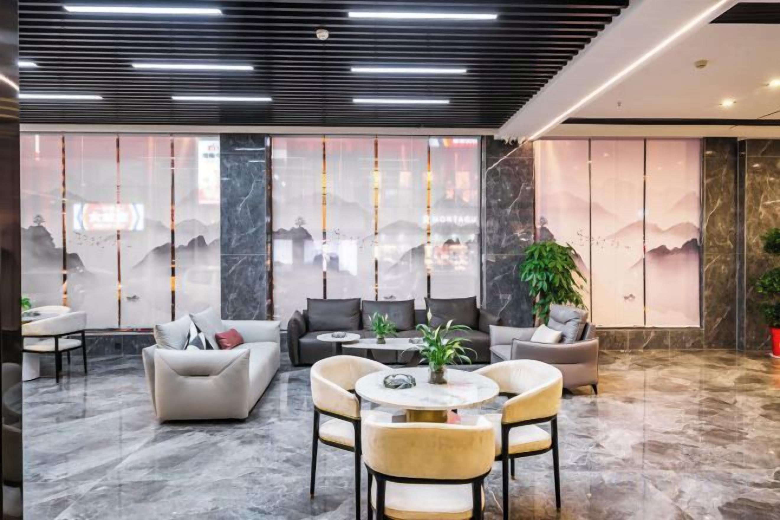 A modern lobby with seating arrangements, a large window with a view, and a decorative plant.