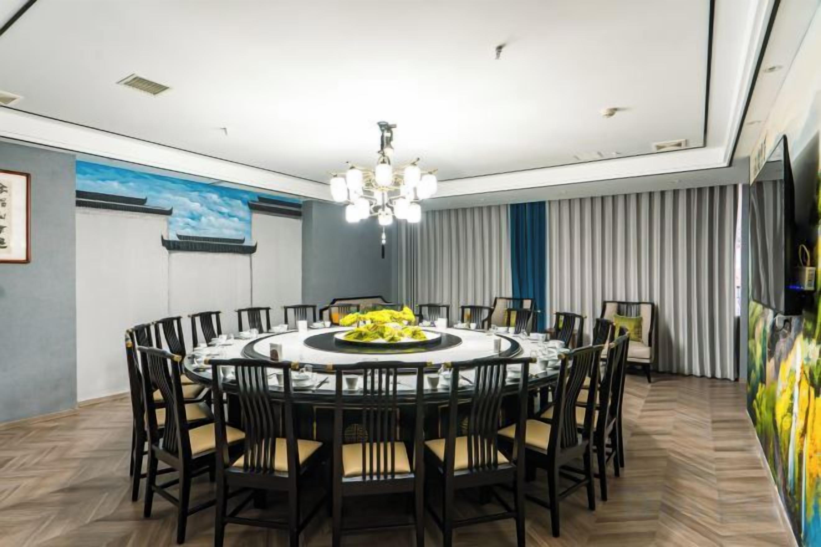 A dining area with a round table, chairs, and a chandelier.