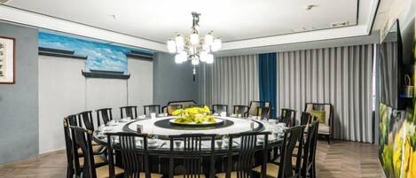 A dining area with a round table, chairs, and a chandelier.
