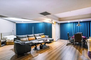 A modern hotel room with a sofa, coffee table, and dining area.