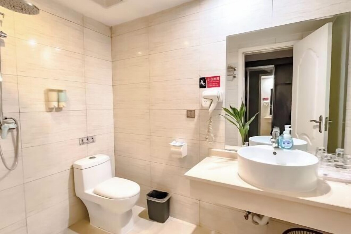 A modern bathroom with a toilet, bidet, sink, and mirror.