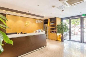 A reception area with a reception desk, a plant, and a view of the outside through glass doors. - IU Hotel (Chongqing Fengcheng) (Chongqing)