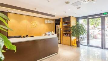 A reception area with a wooden reception desk, a clock, and a plant.