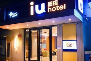 A hotel entrance with a glass door, a sign with the hotel name, and a reception area visible inside. - IU Hotel (Chongqing Fengcheng) (Chongqing)