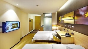 Hotellihuone, jossa on kaksi sänkyä, televisio, työpöytä ja kylpyhuone.