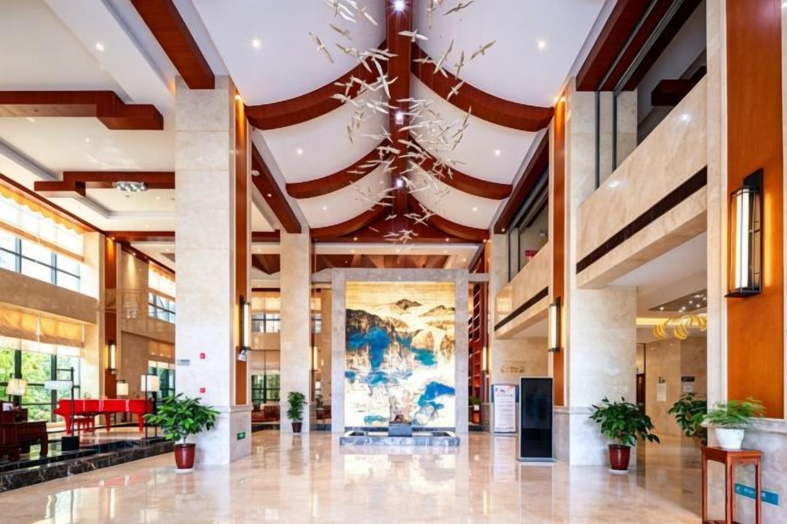 A spacious lobby with a high ceiling, large windows, and a central art installation.