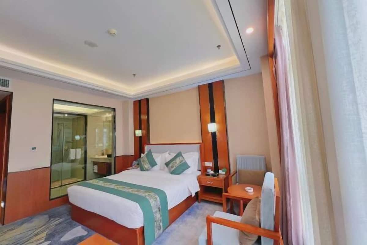 A hotel room with a large bed, bedside tables, a desk, and a chair.