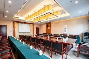A conference room with a long table, chairs, a projector screen, and a television. - Hongyuehu Hotel (Luliang)