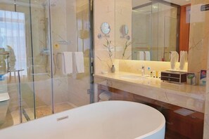 A modern bathroom with a glass-enclosed shower, a large white bathtub, and a vanity with a mirror and toiletries. - Hongyuehu Hotel (Luliang)