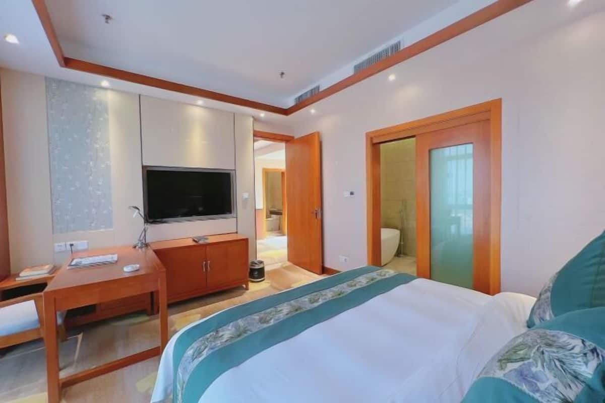 A hotel room with a bed, a TV, a desk, and a wardrobe.