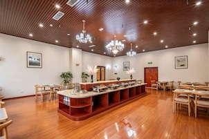 Una habitación amplia con suelo de madera, mostrador de recepción y varias zonas de estar.