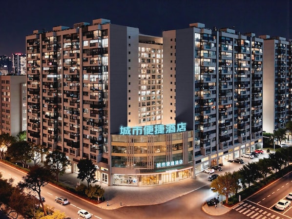 A multi-story hotel with a modern design, featuring a prominent entrance and a well-lit facade.