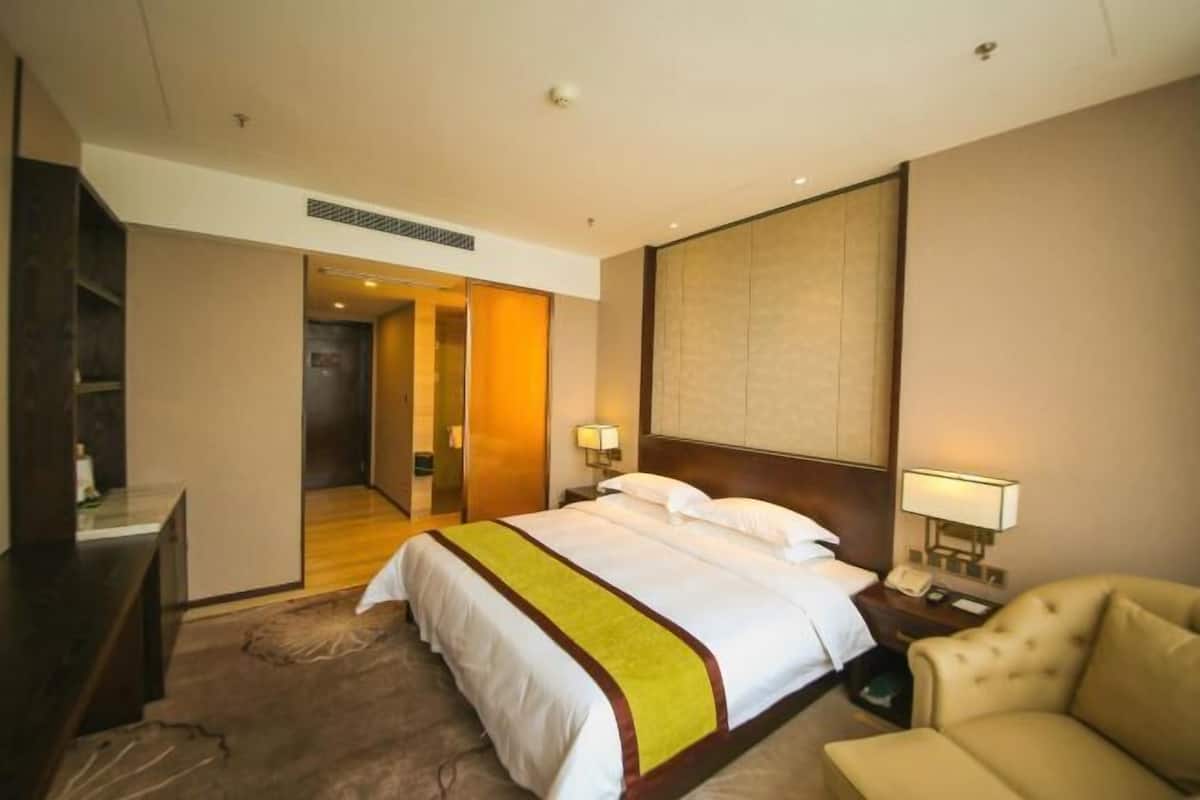 Ein Hotelzimmer mit Bett, Nachttisch, Lampe und einem Sessel.