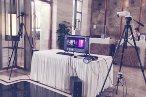 A conference room with a white table, a computer, and two tripods with cameras.