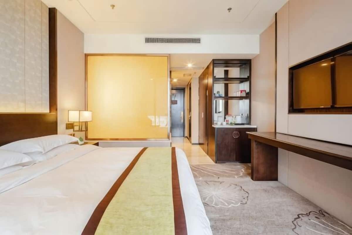 Ein Hotelzimmer mit Bett, Schreibtisch, Spiegel und einem sichtbaren Badezimmer im Hintergrund.