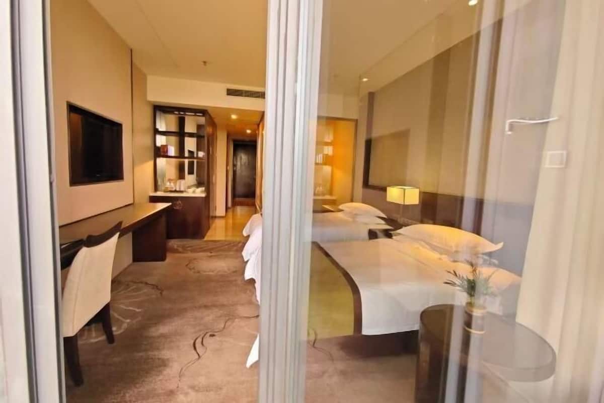 Ein Hotelzimmer mit Bett, Nachttisch, Lampe und Blick durch eine Glastür.