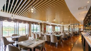 Un vaste espace dédié à la salle à manger, avec de nombreuses tables et chaises, de grandes fenêtres et un design moderne au niveau du plafond.