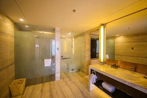 Een moderne badkamer met een douchecabine van glas, een grote spiegel en een marmeren vloer.